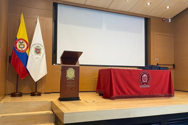 Un podio con un mantel rojo delante de una pantalla grande.