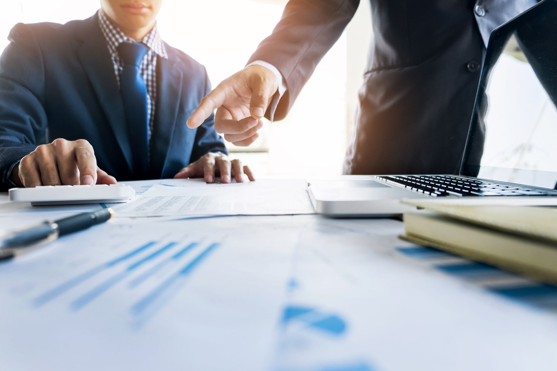 A Man is Pointing at Something While Another Man is Using a Calculator