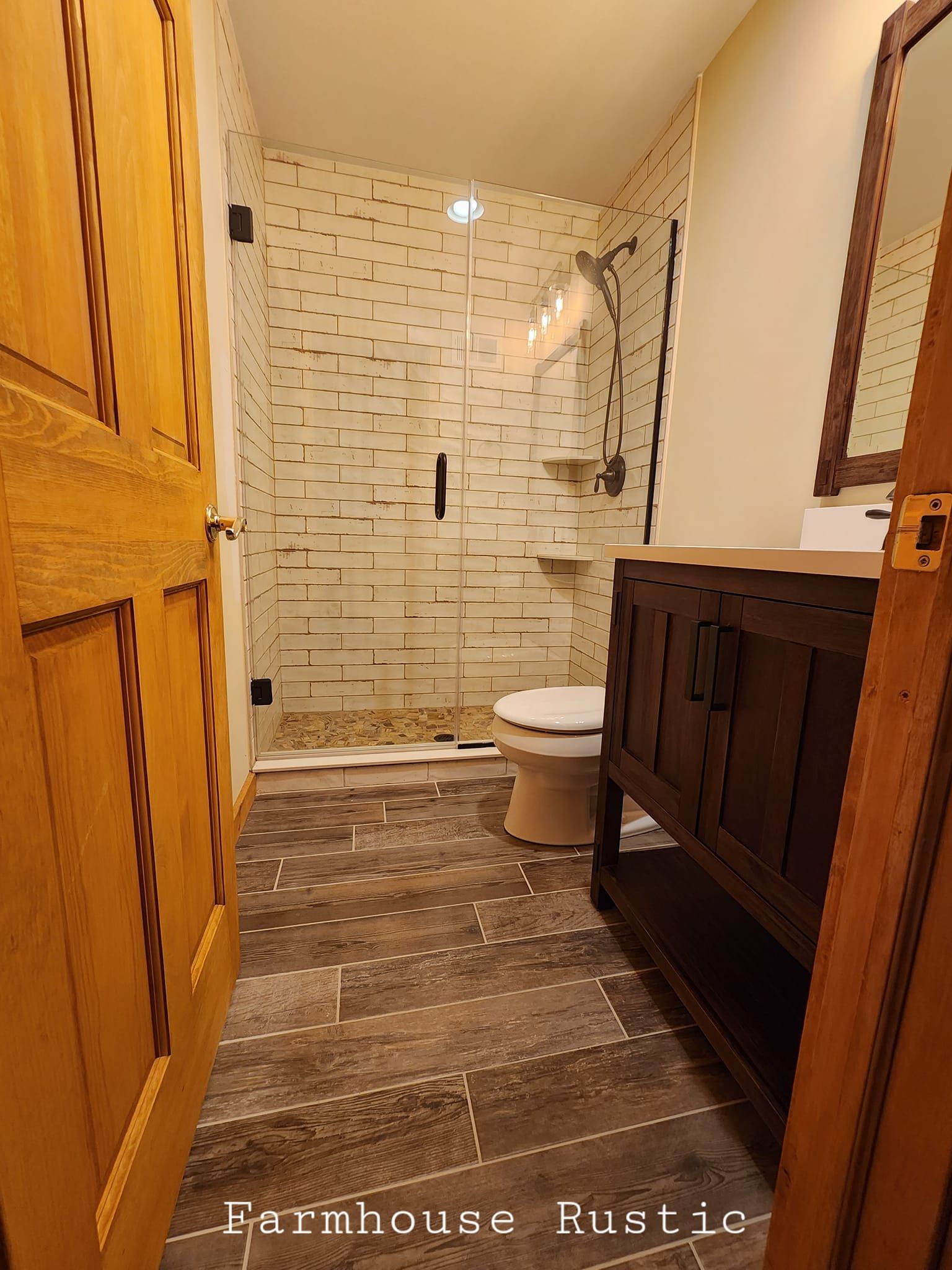 A bathroom with a toilet , sink , mirror and shower.