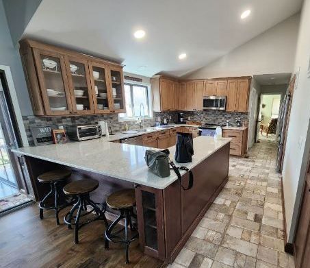 A kitchen with wooden cabinets and stools and a large island.