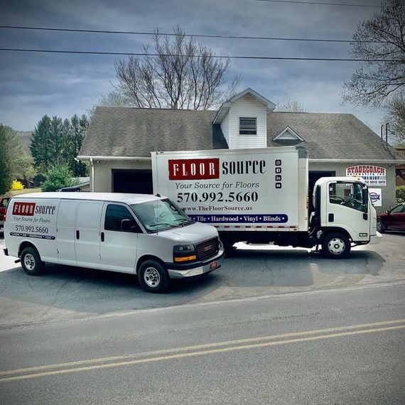 Two white vans are parked next to a flour source truck