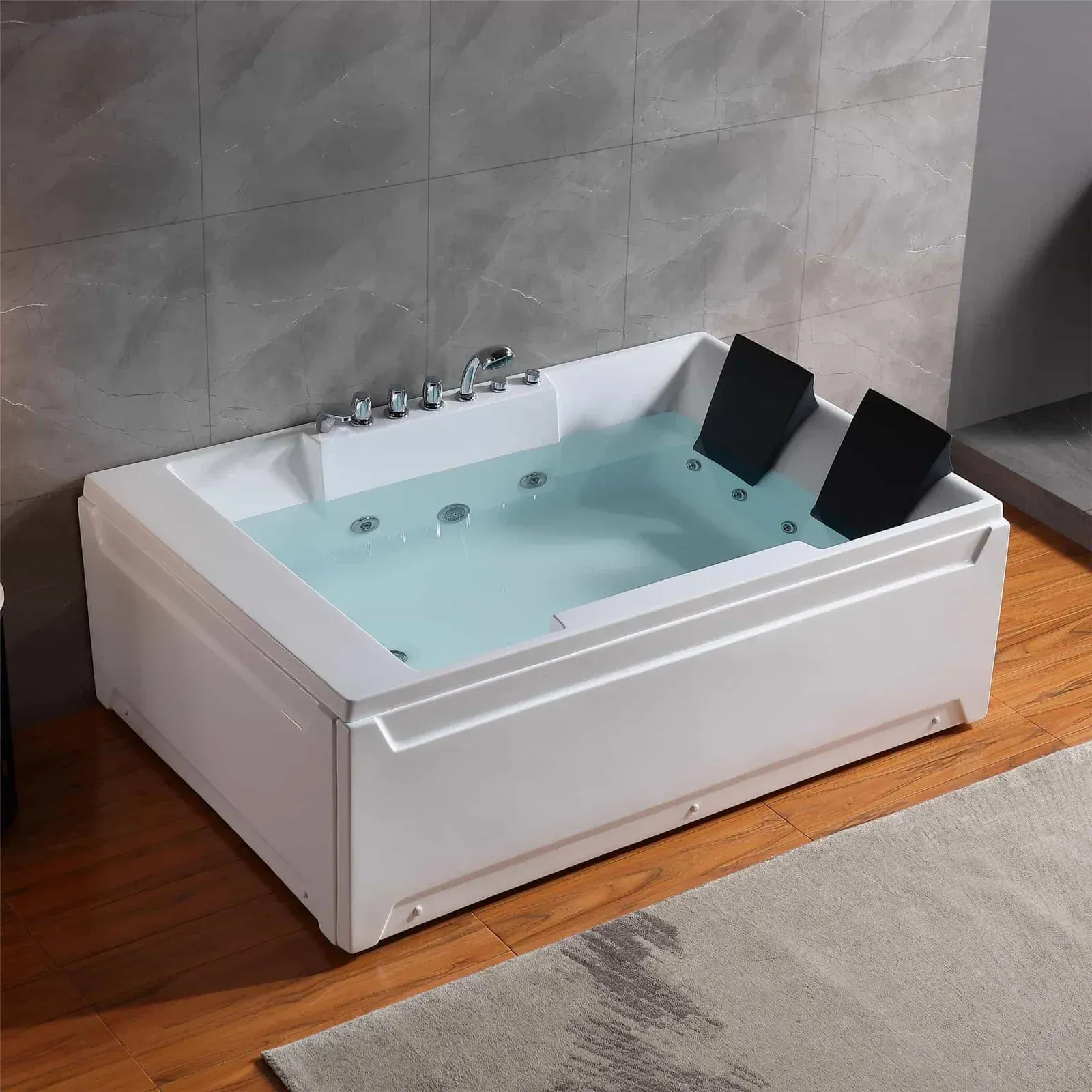 White rectangular jacuzzi with filled water, black headrests, and chrome fixtures, indoors on a wood floor.