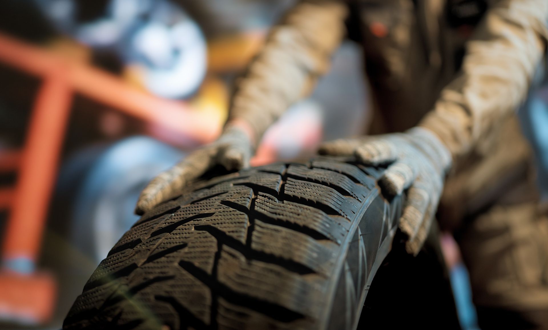 A close up of a person holding a tire in a garage.