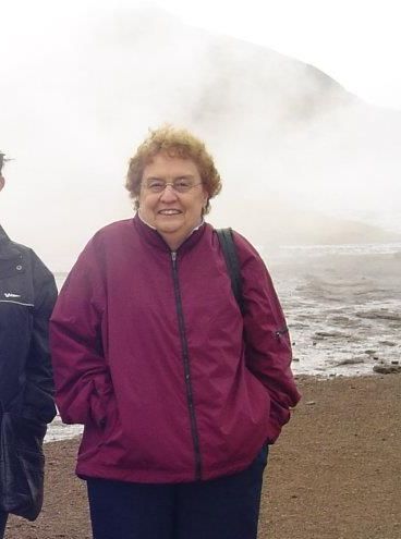 A woman in a purple jacket is standing on a beach next to a man.