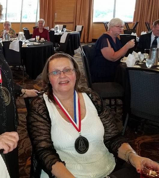 A woman wearing a medal is sitting at a table with other people