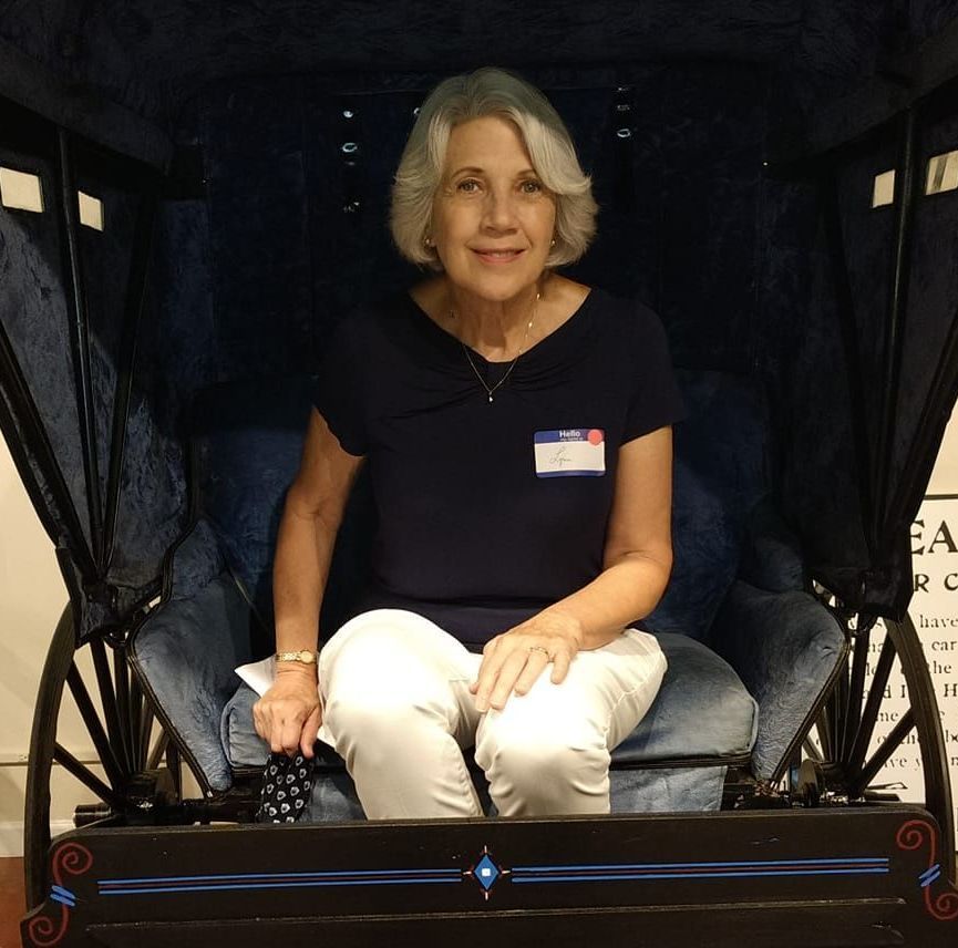 A woman is sitting in a chair with a name tag on her chest