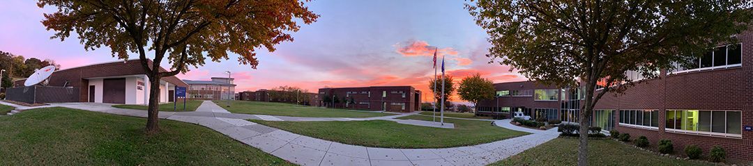 A panoramic view of a residential neighborhood with a sunset in the background.