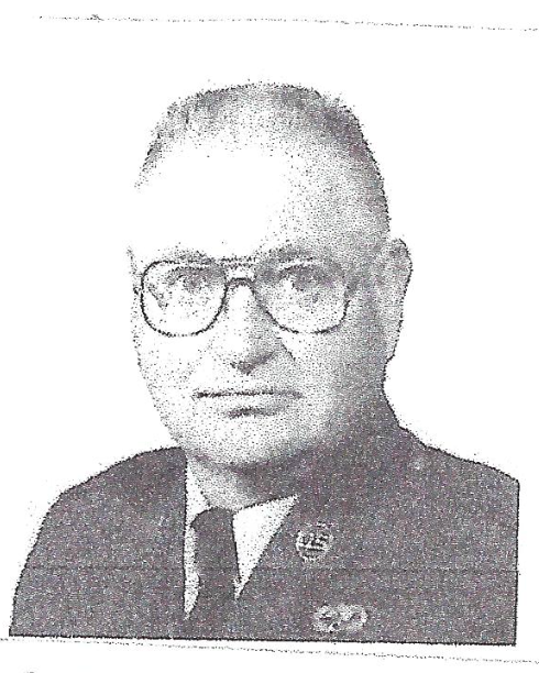 A black and white photo of a man wearing glasses and a suit and tie.