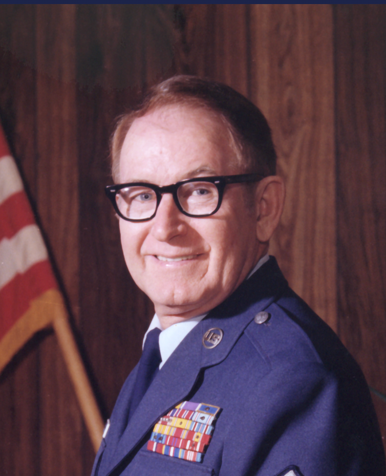 A man in a military uniform is smiling in front of an american flag