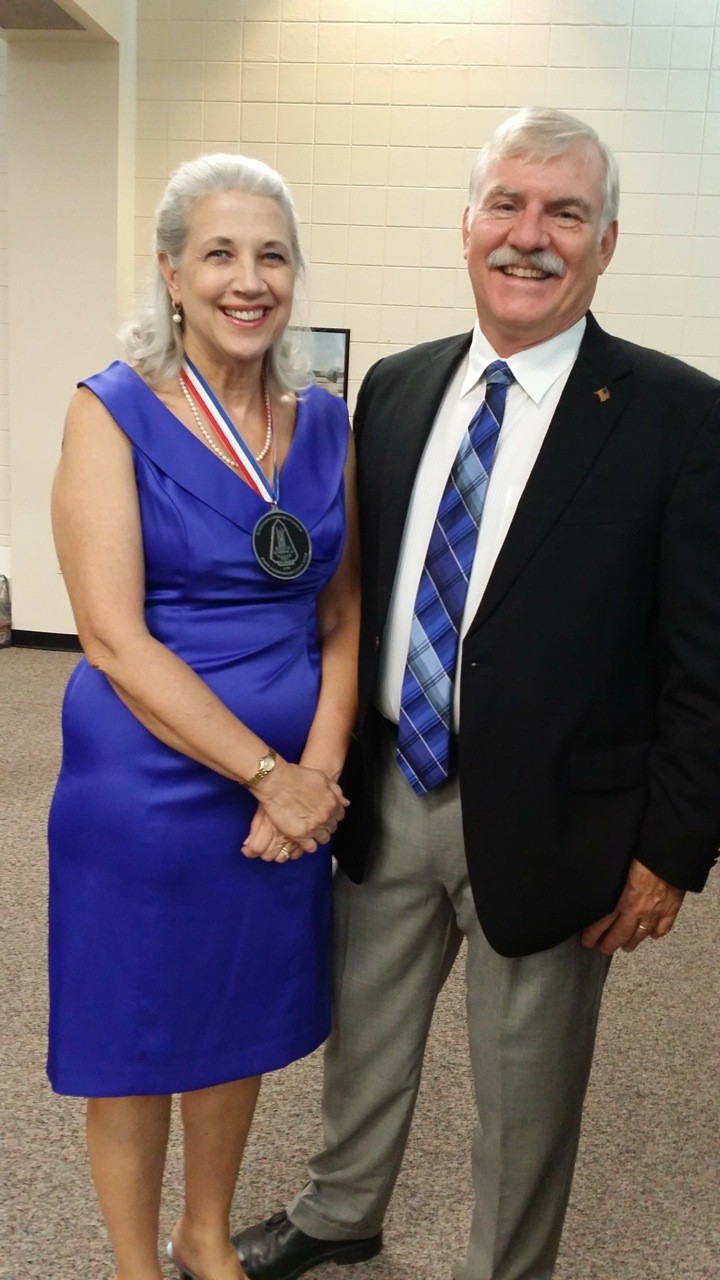 A woman in a blue dress is standing next to a man in a suit and tie