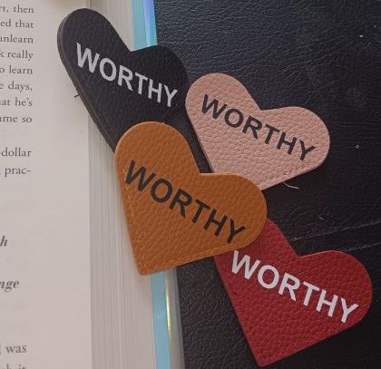 A close up of a book with a bookmark that says worthy on it.
