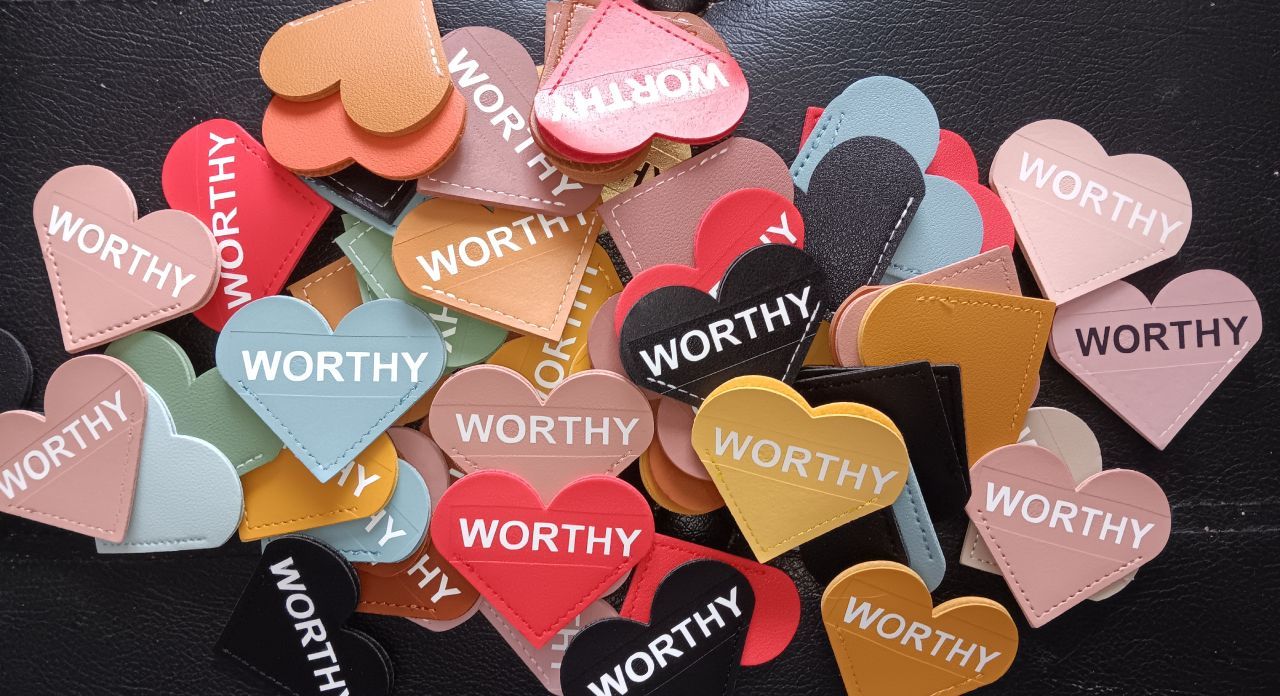 A pile of heart bookmarks with the word worthy on them