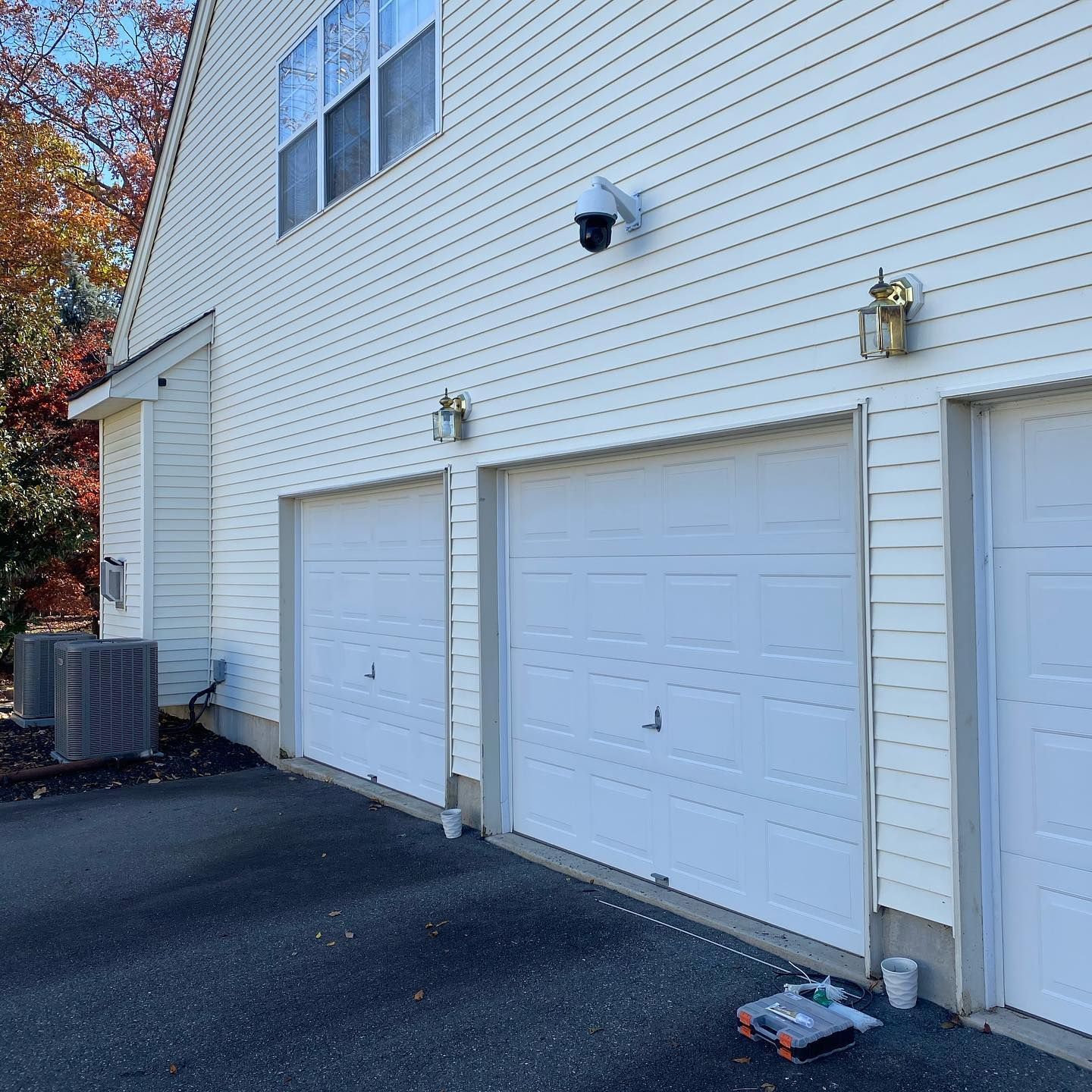 A white house with three garage doors and a camera on the side
