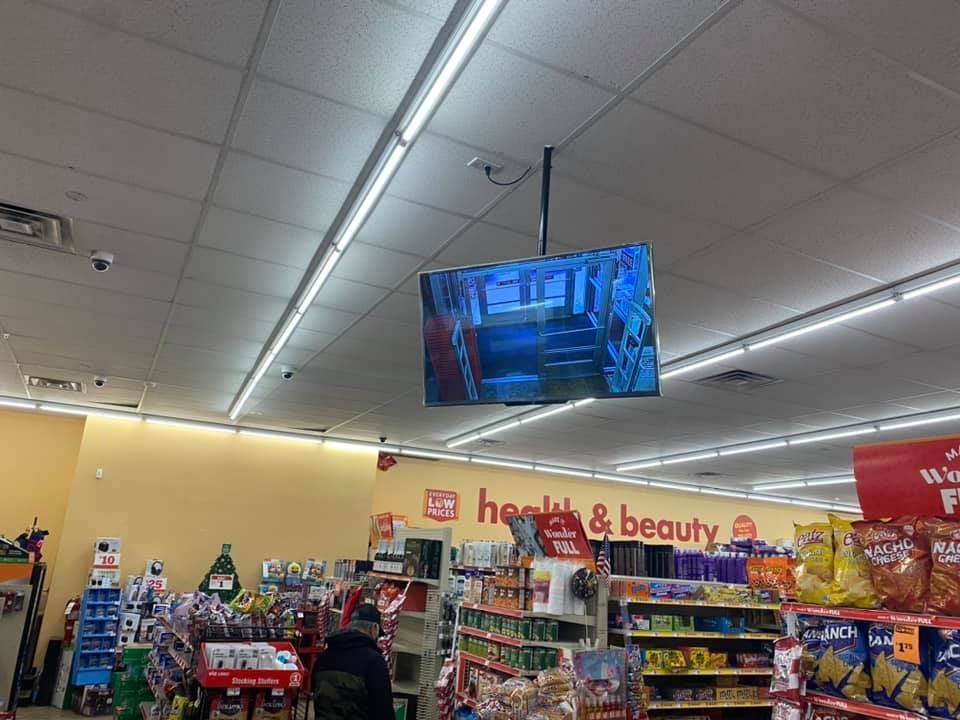 A tv is hanging from the ceiling of a grocery store.