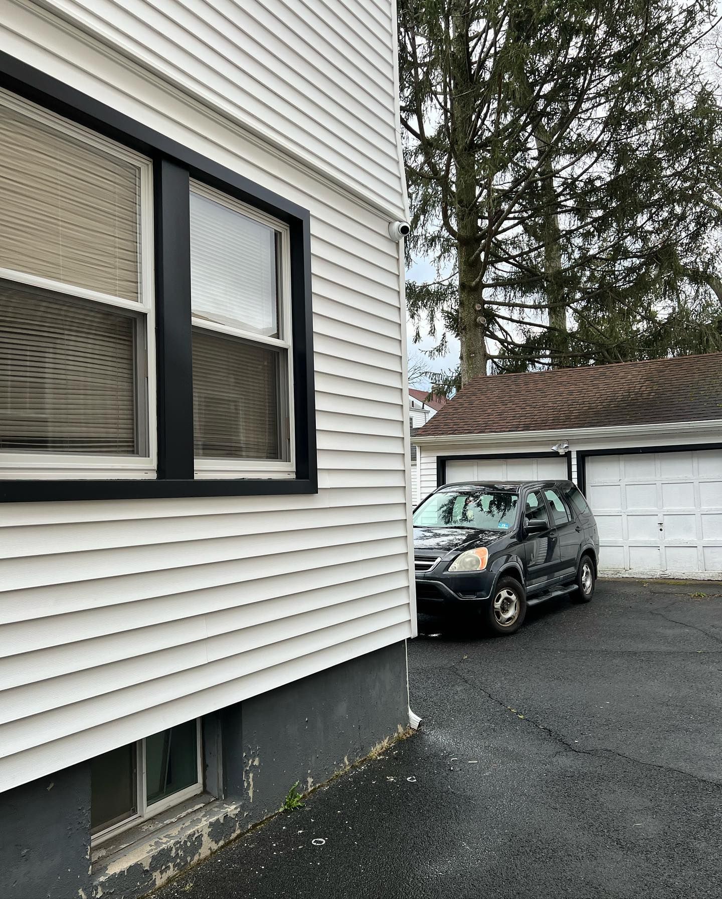 A black car is parked in front of a white house