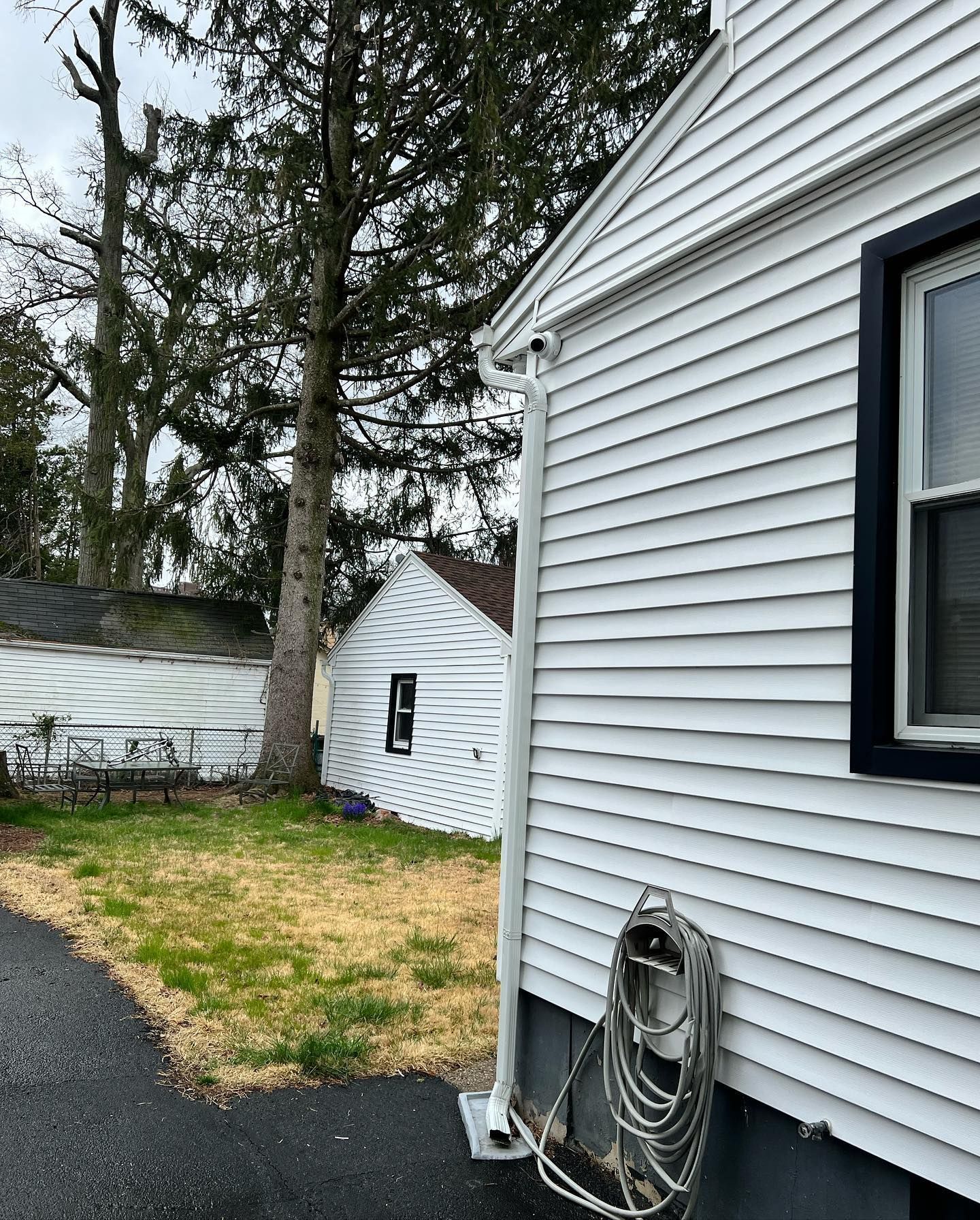 A white house with a hose attached to the side of it.