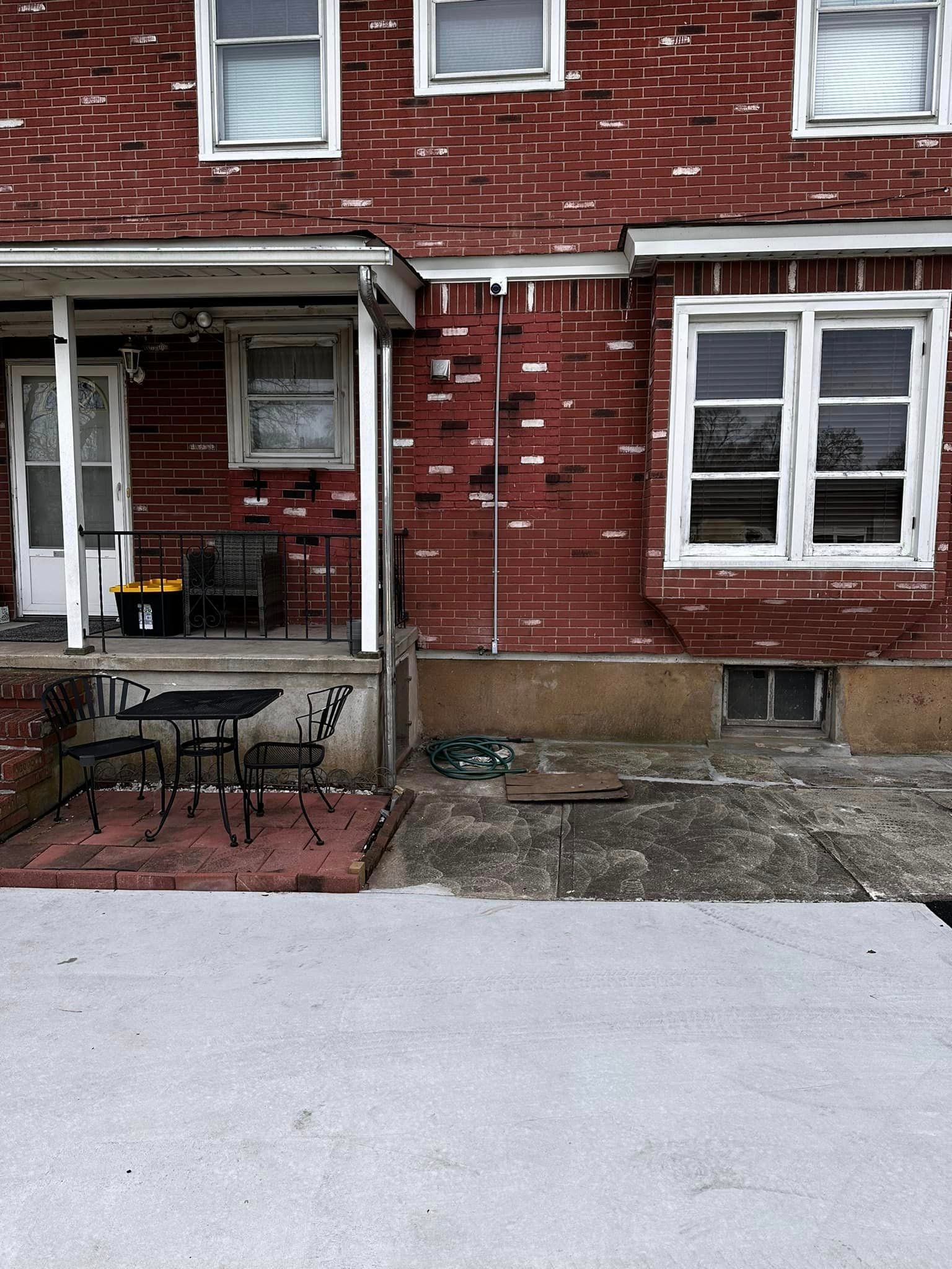 A red brick house with a table and chairs on the porch
