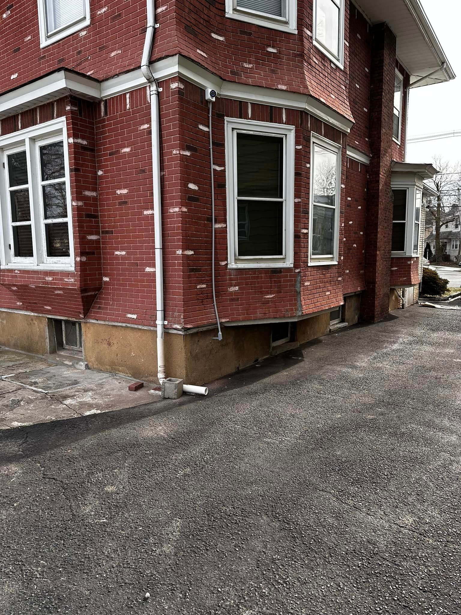 A red brick house with white windows and a driveway.