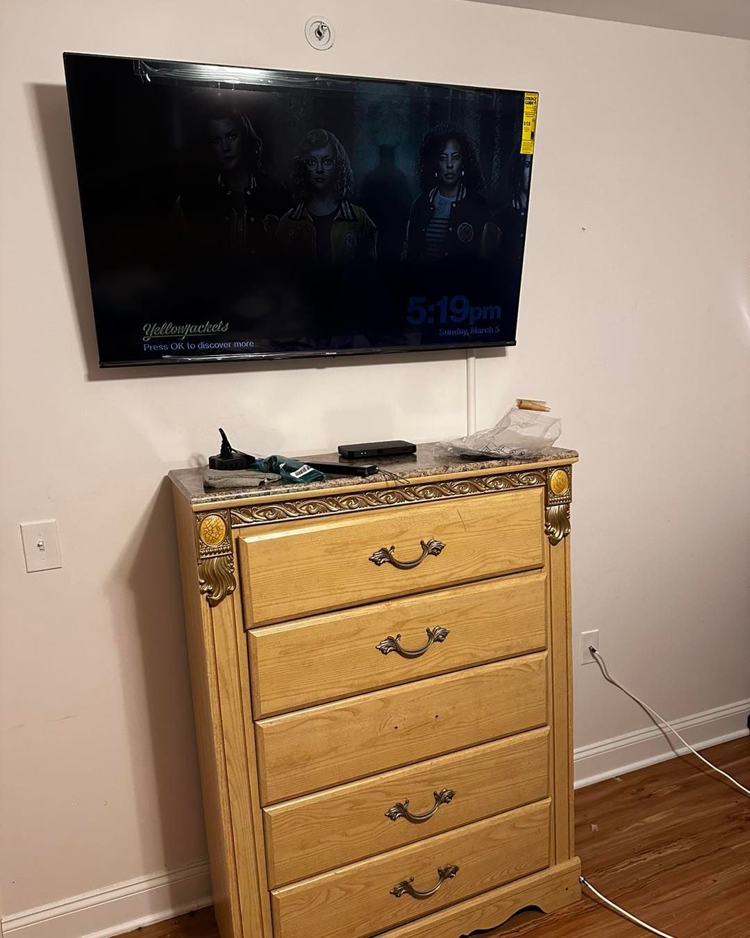 A bedroom with a dresser and a flat screen tv on the wall.