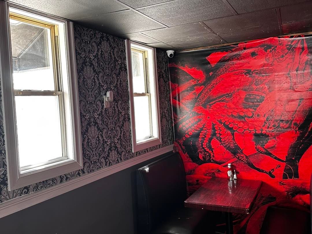 A room with a table and chairs and a red wall.