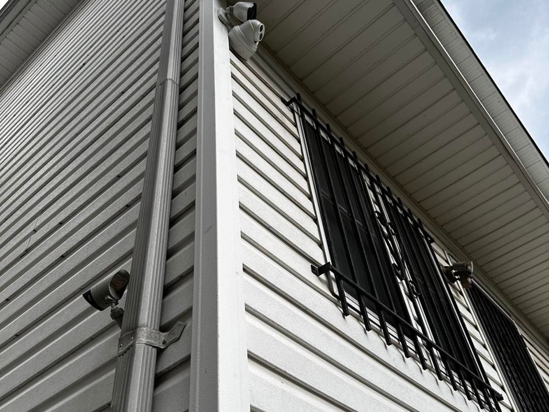 A black and white photo of the side of a house with a window.