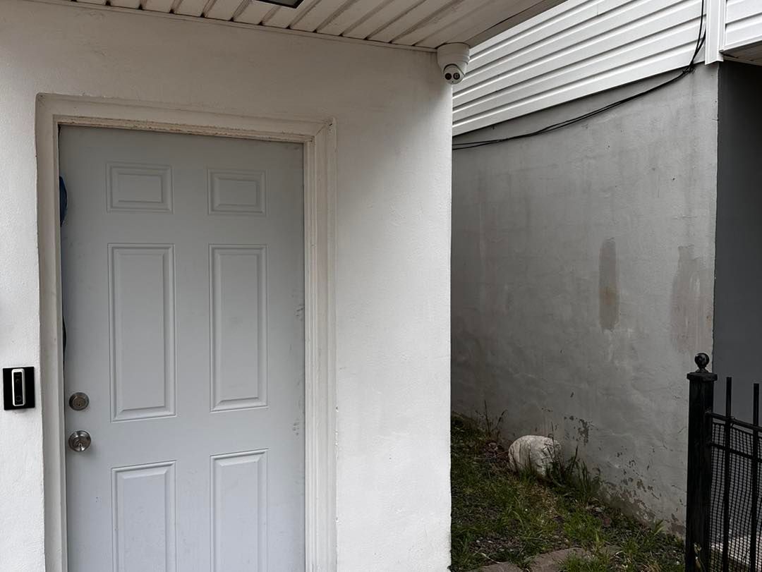 A white door is sitting on a white wall next to a fence.