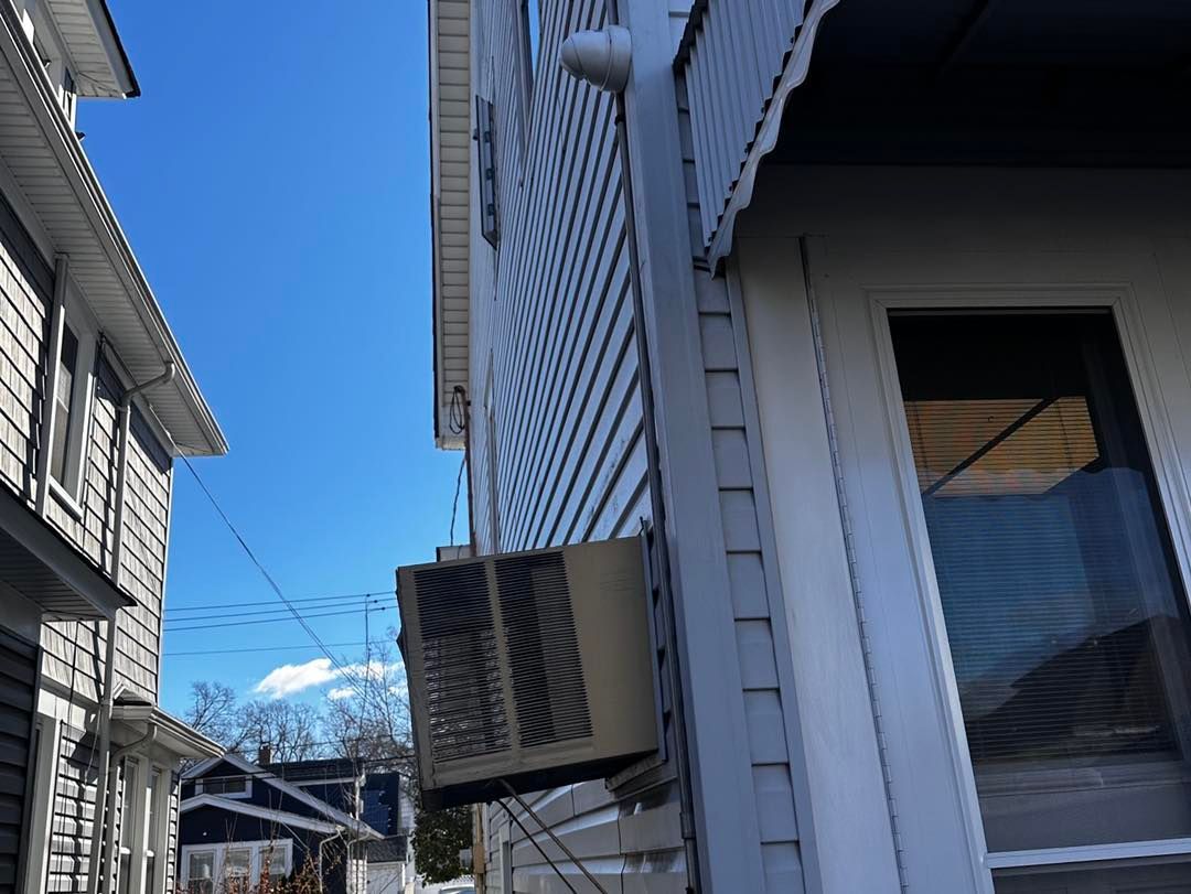 A white house with a window air conditioner on the side