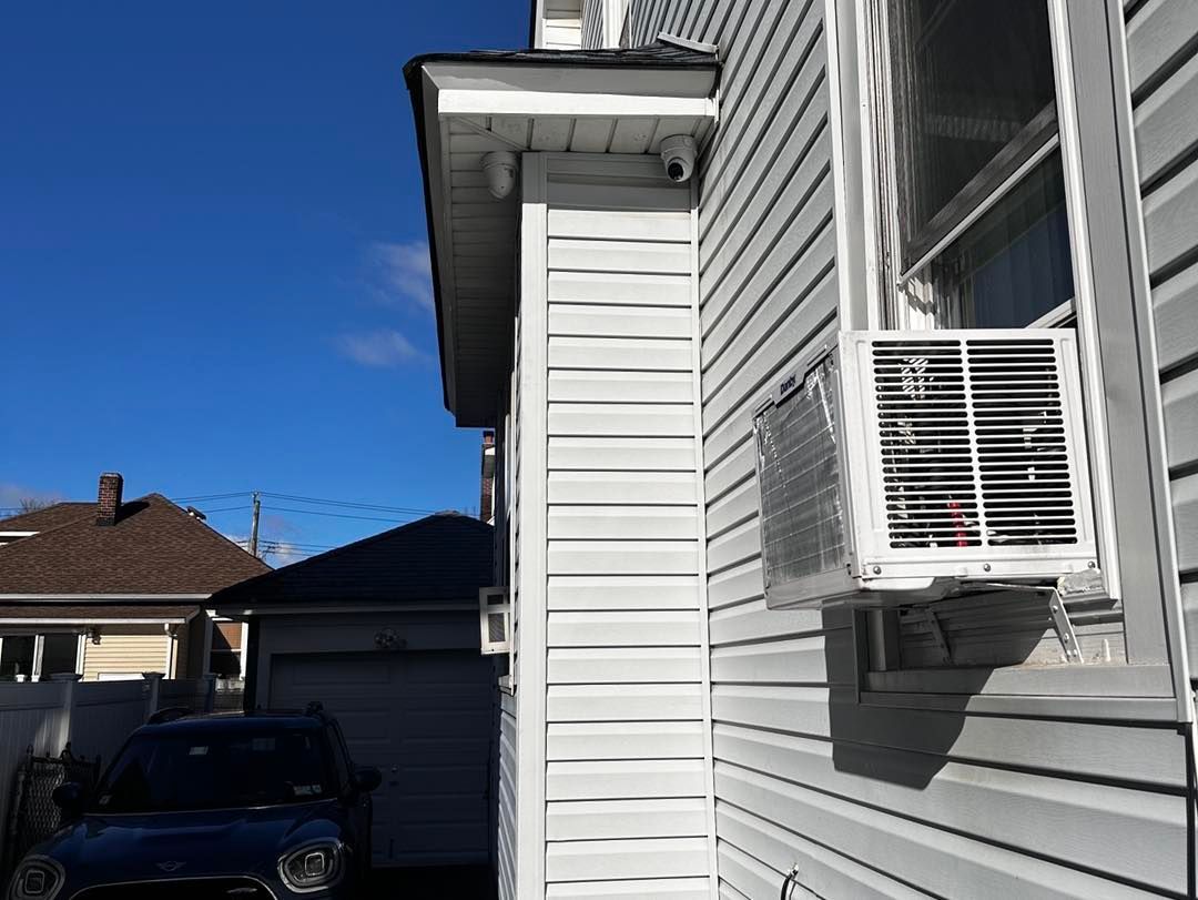 A blue car is parked in front of a white house.