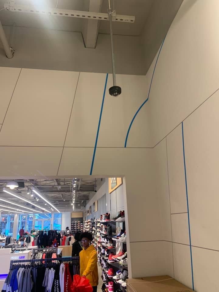 A man in a yellow jacket is standing in a shoe store.