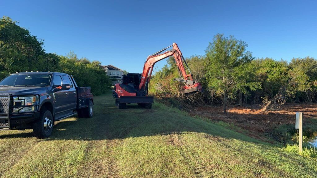 A truck is parked next to an excavator in a field.