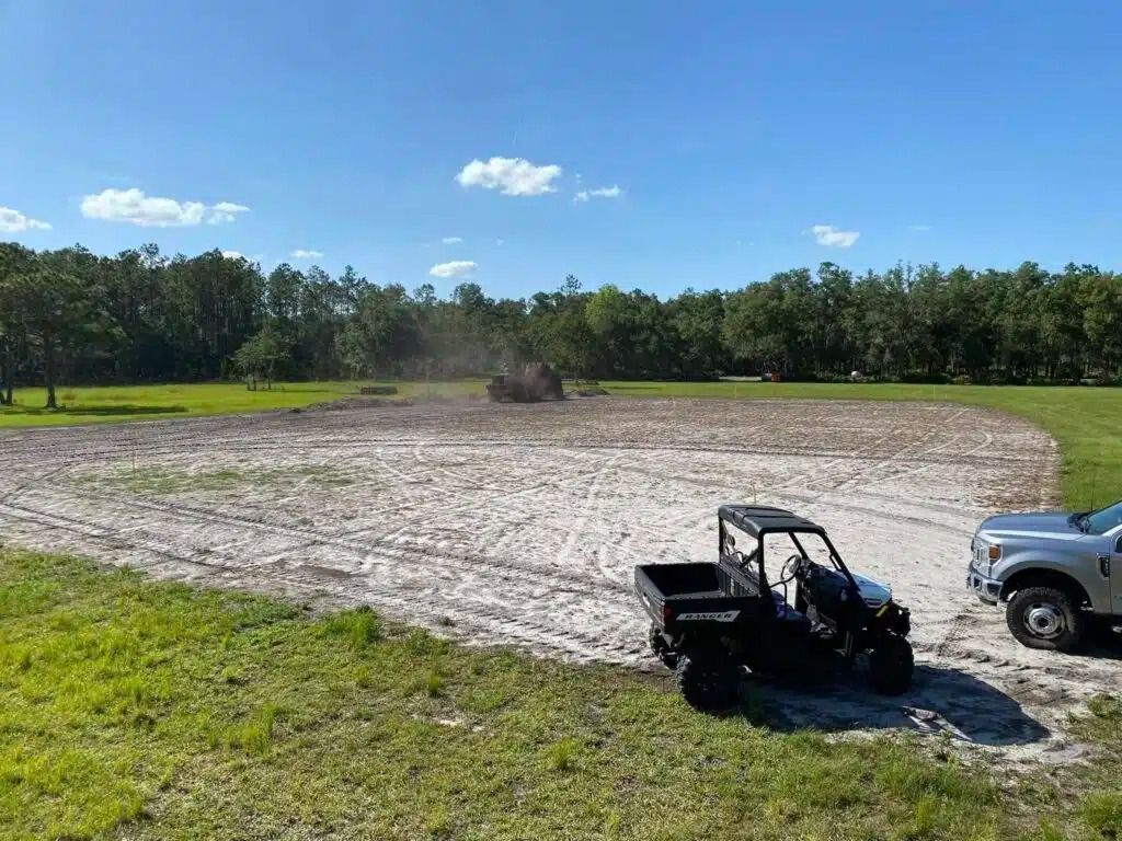 A truck is parked next to an excavator in a field.