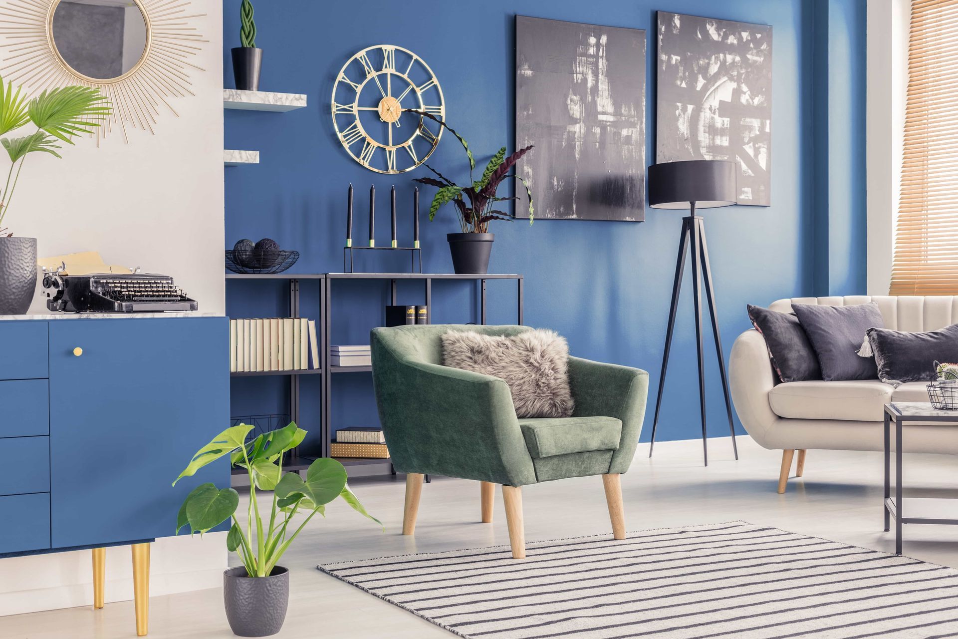 Modern living room with blue cabinets, green and beige chairs, wall art, and a large mirror
