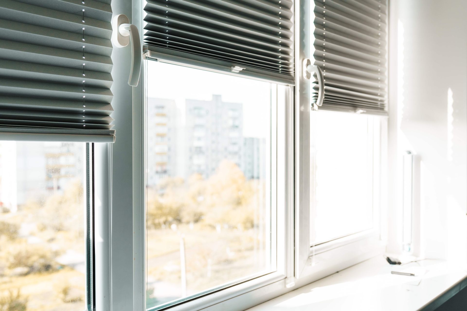 Bright window with partially closed blinds and a city view outside