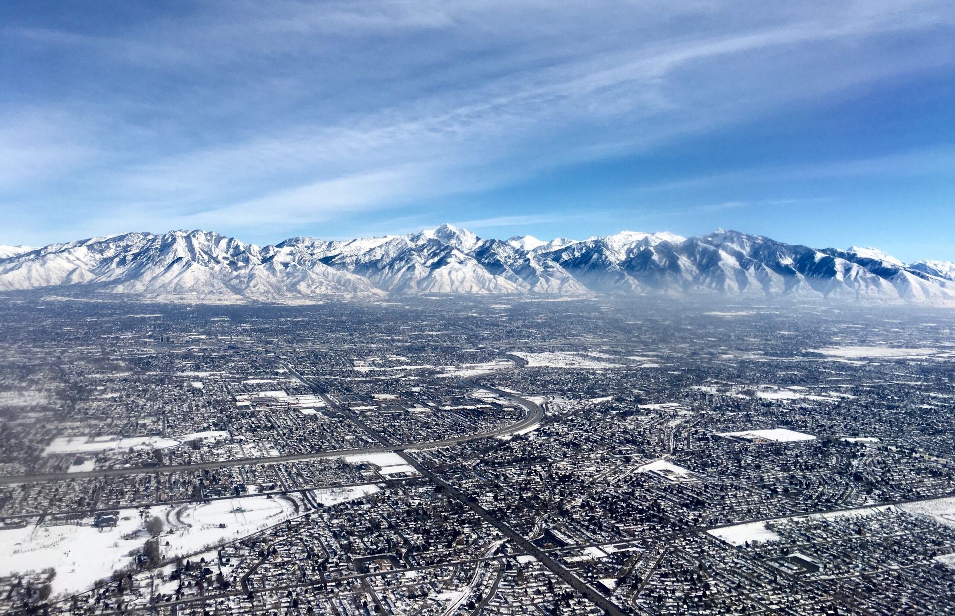 An aerial view of a snowy city with mountains in the background.