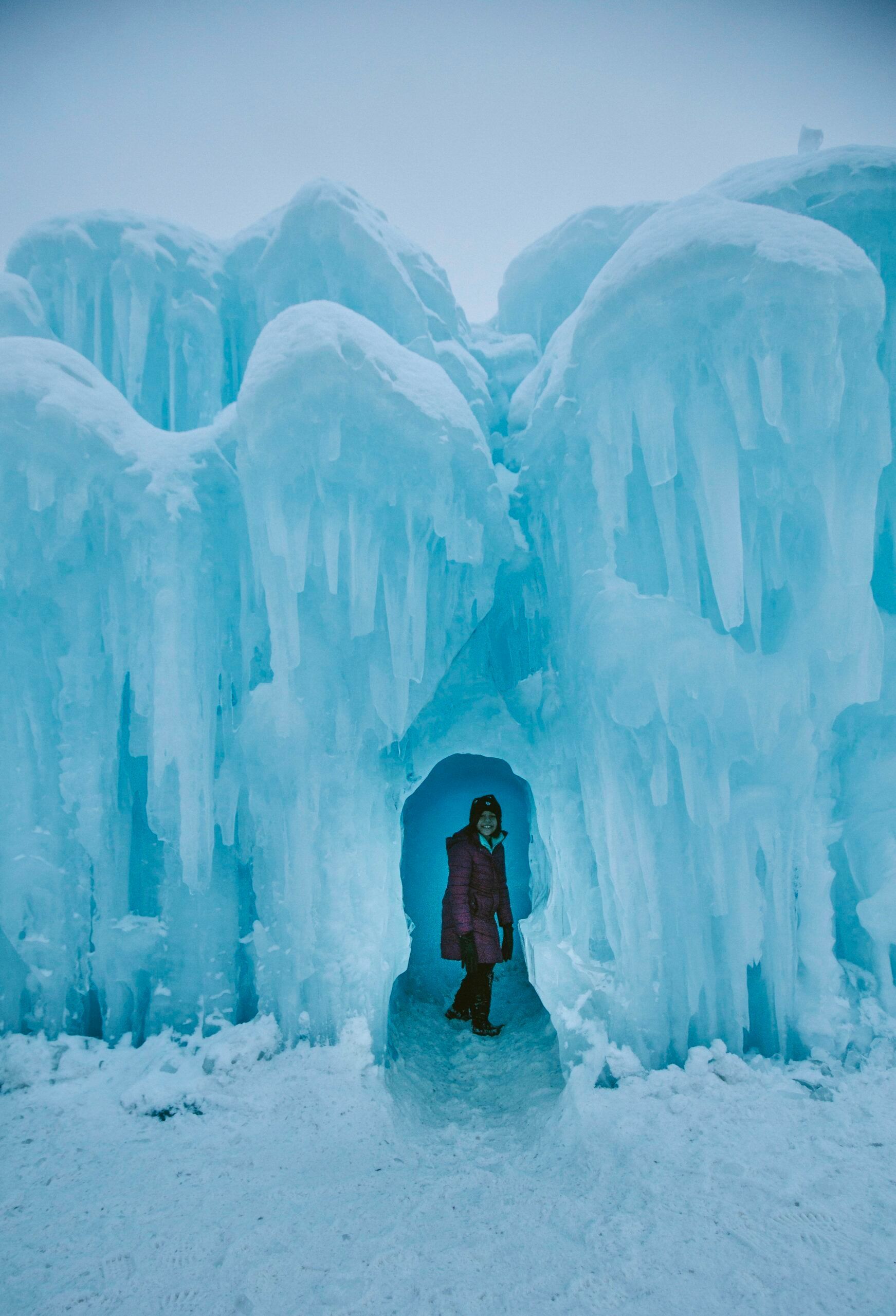 A woman is standing in the middle of an ice castle.