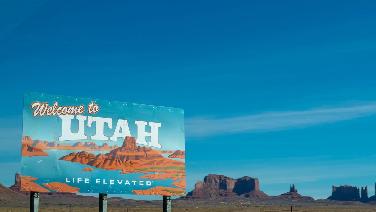 A welcome to utah sign in the middle of a desert.