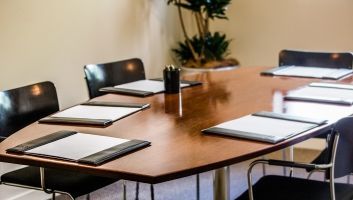 A conference room with a long wooden table and chairs.