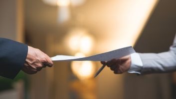 A man is handing a piece of paper to another man.