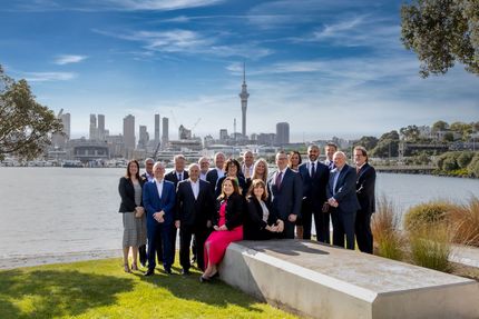 A group of people are posing for a picture in front of a body of water.