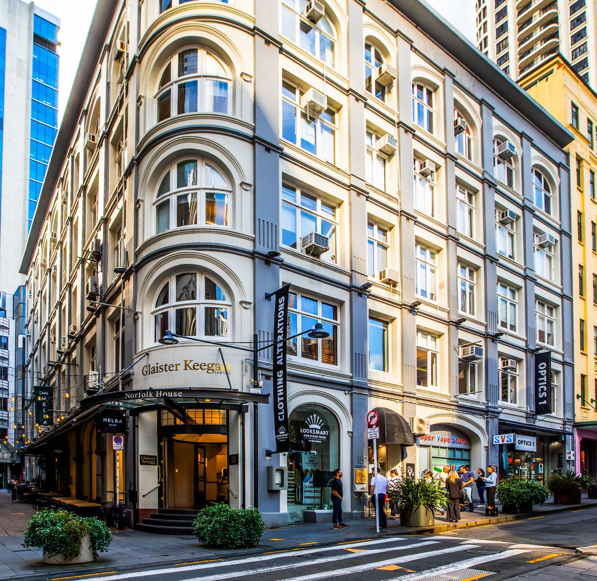A car is driving down a city street in front of a large building.