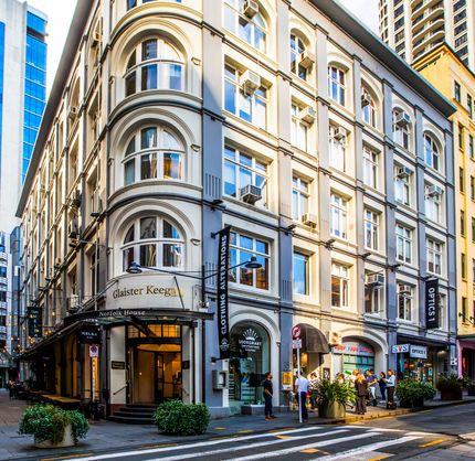 A car is driving down a city street in front of a large building.