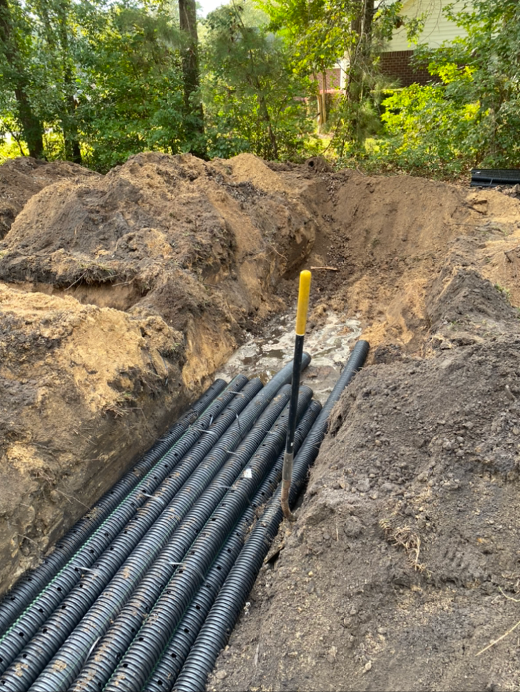 a yellow shovel is in the dirt next to a bunch of black pipes