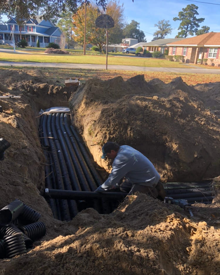 a man is kneeling in the dirt working on a pipe