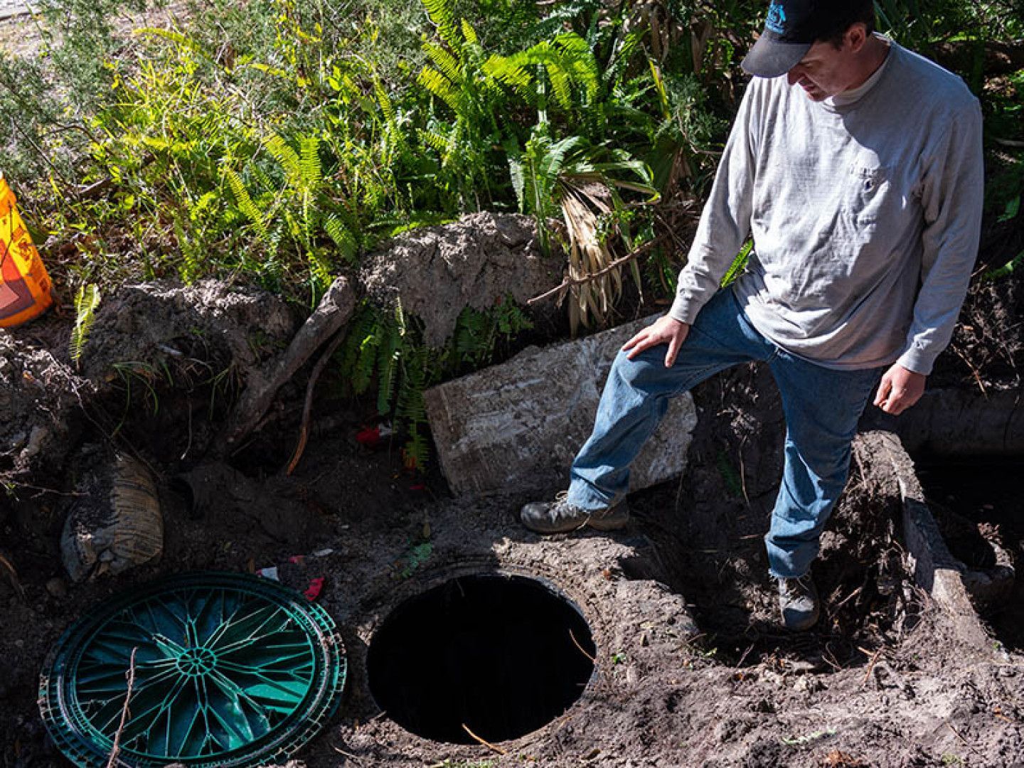 a man wearing a ny hat is standing in the dirt