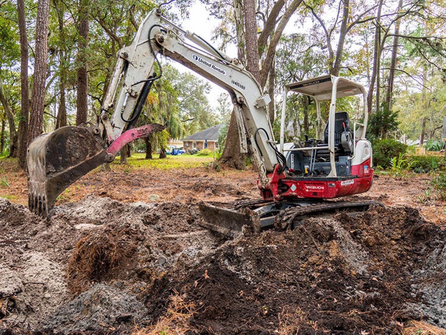 a white and red excavator with united rentals written on the side