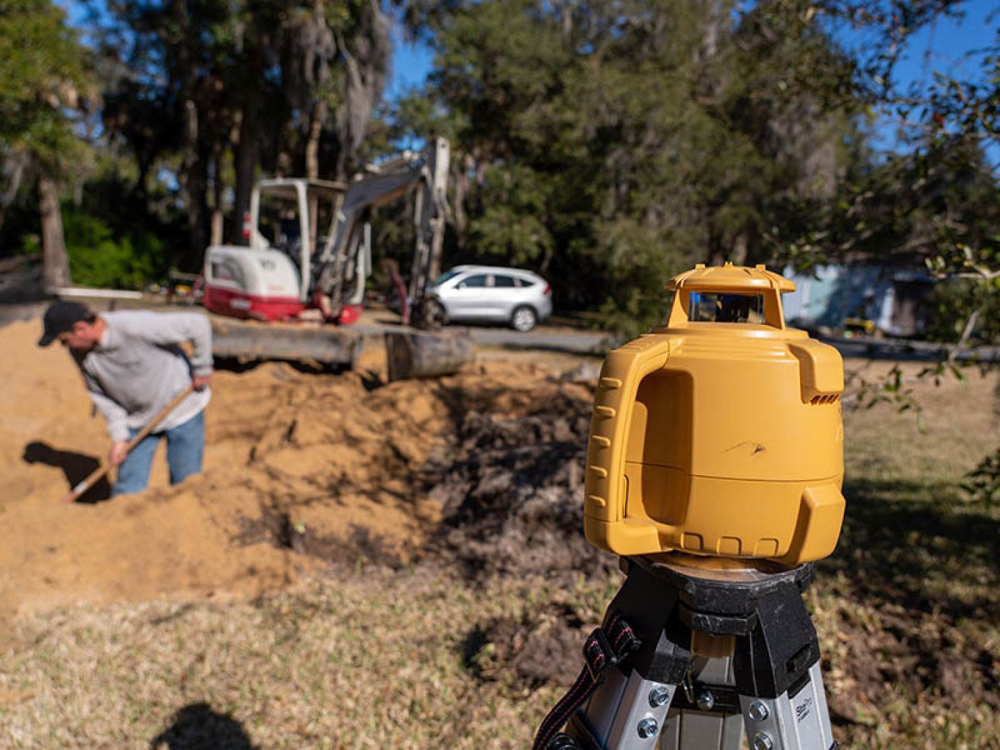 a man is digging in the dirt with a shovel in the background
