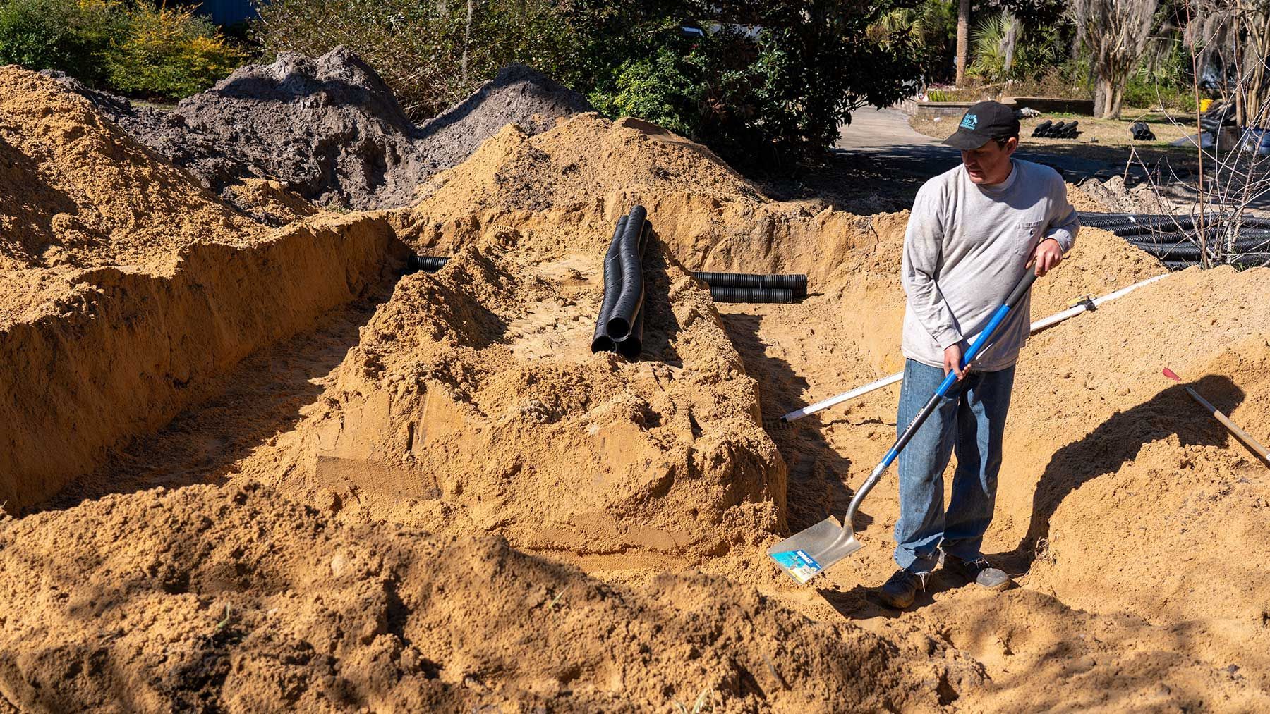 a man wearing a hat with the letter t on it is digging in the dirt