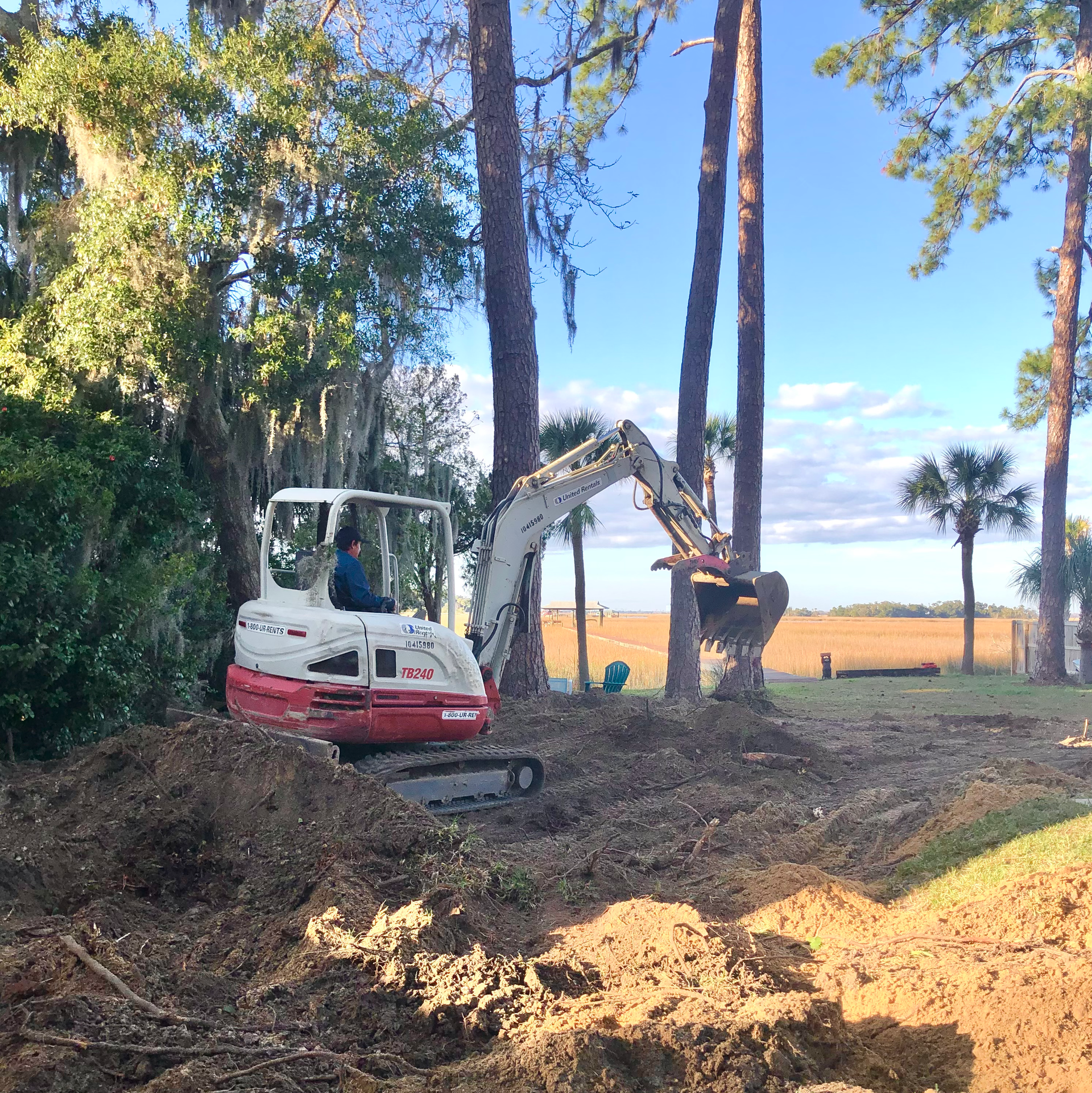 a man is driving a white and red excavator that says takeuchi