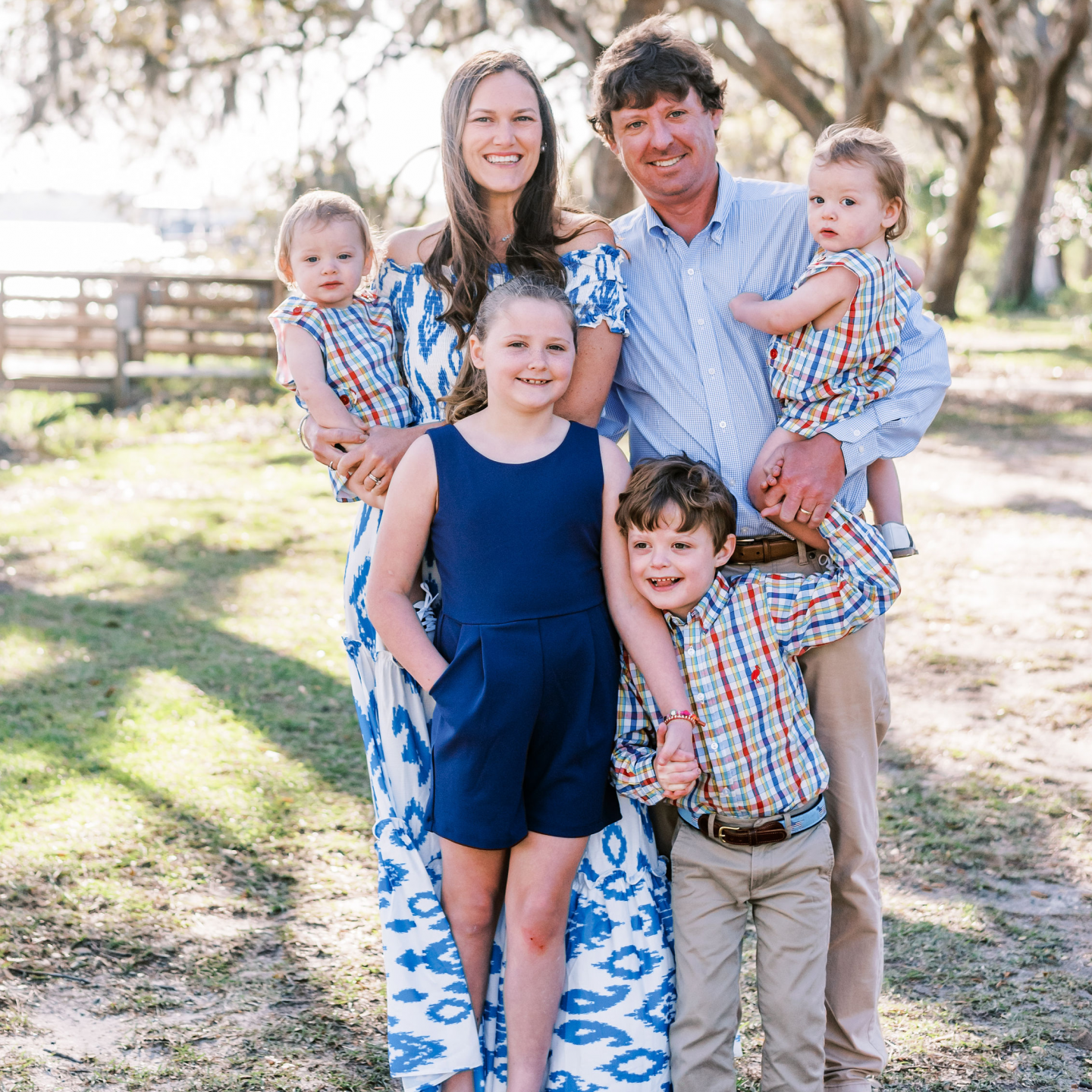 a family posing for a picture in a field with trees in the background in Wilmington Island, Georgia