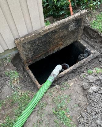 A green hose is connected to a septic tank.